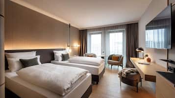 Habitación de hotel con dos camas, un escritorio, una silla y un televisor.