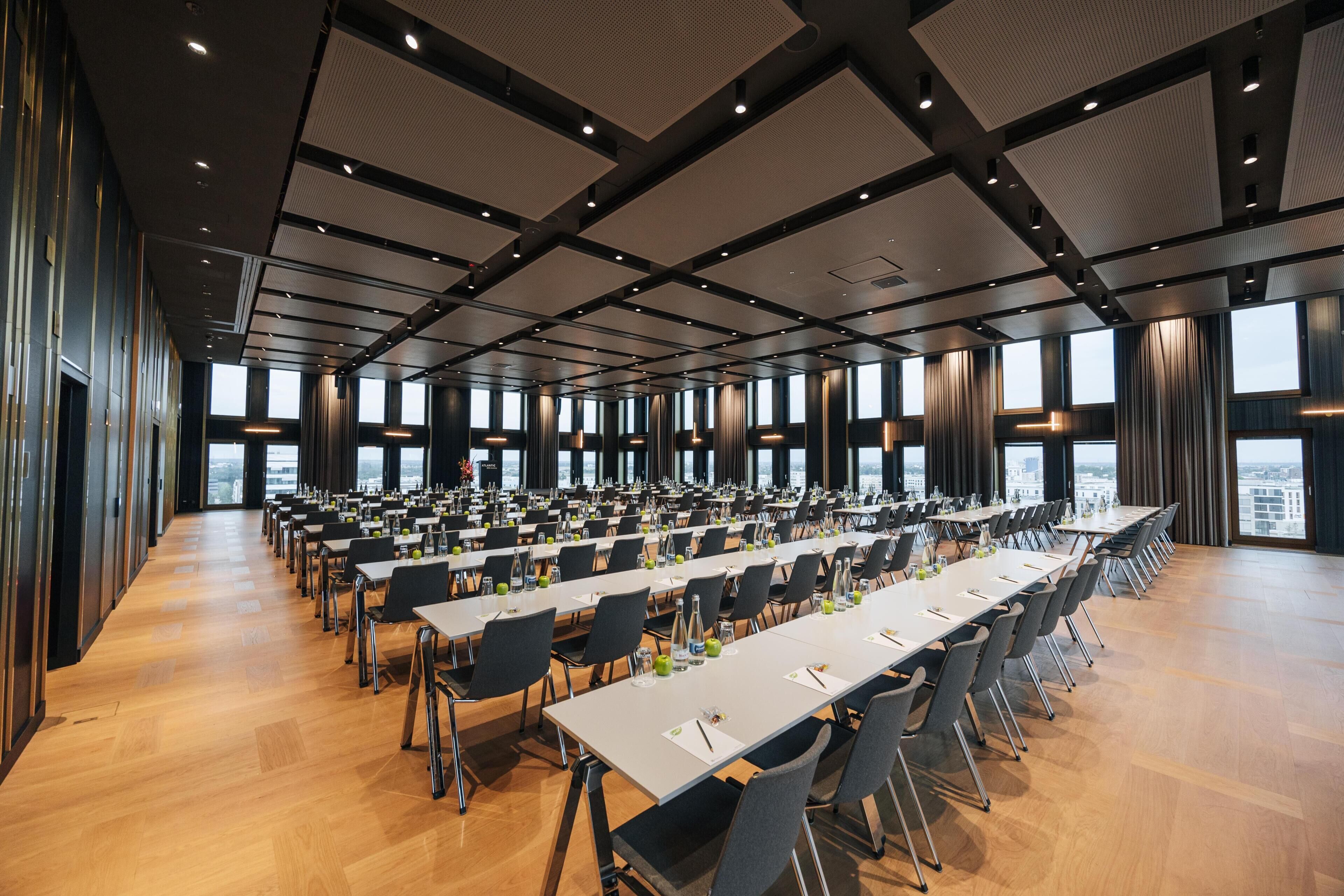 A conference room with long tables, chairs, and city views through large windows.