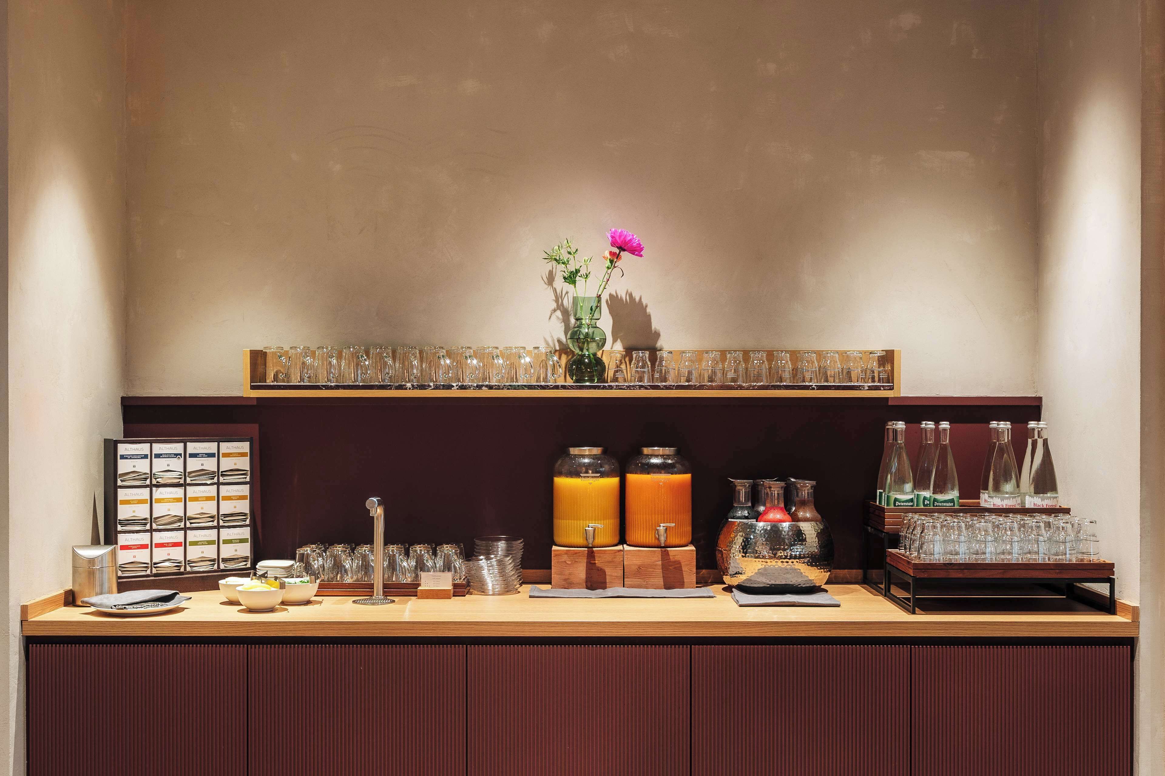 A bar area with a wooden counter, glassware, and two orange juice dispensers.