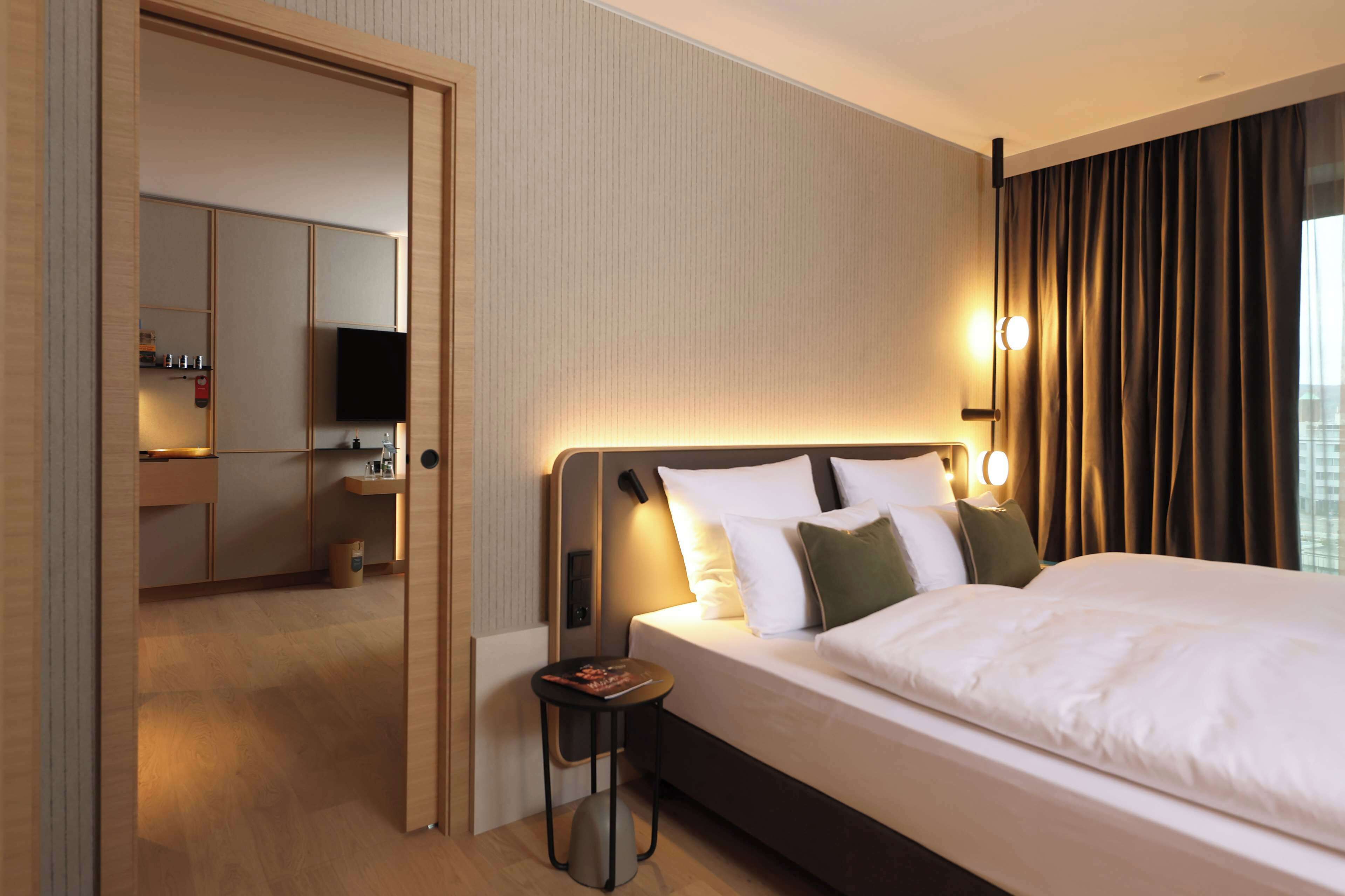 A hotel room with a bed, bedside table, and a TV.