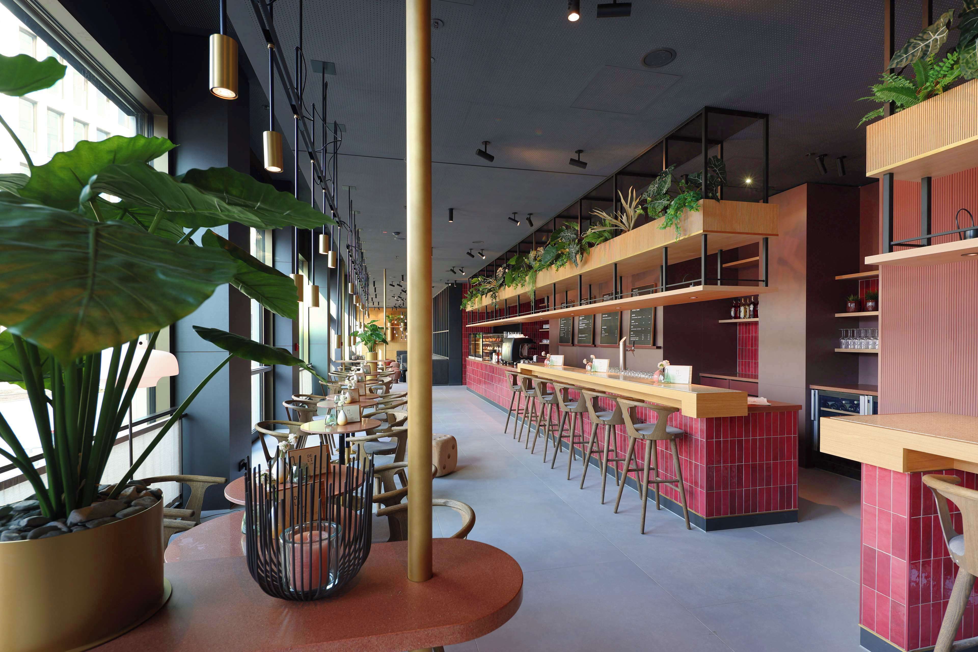 A modern restaurant with high ceilings, pendant lighting, and a bar area with stools.