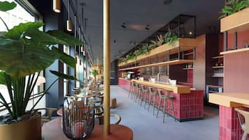 Ein modernes Restaurant mit hohen Decken, Pendelleuchten und einer Bar mit Sitzgelegenheiten.