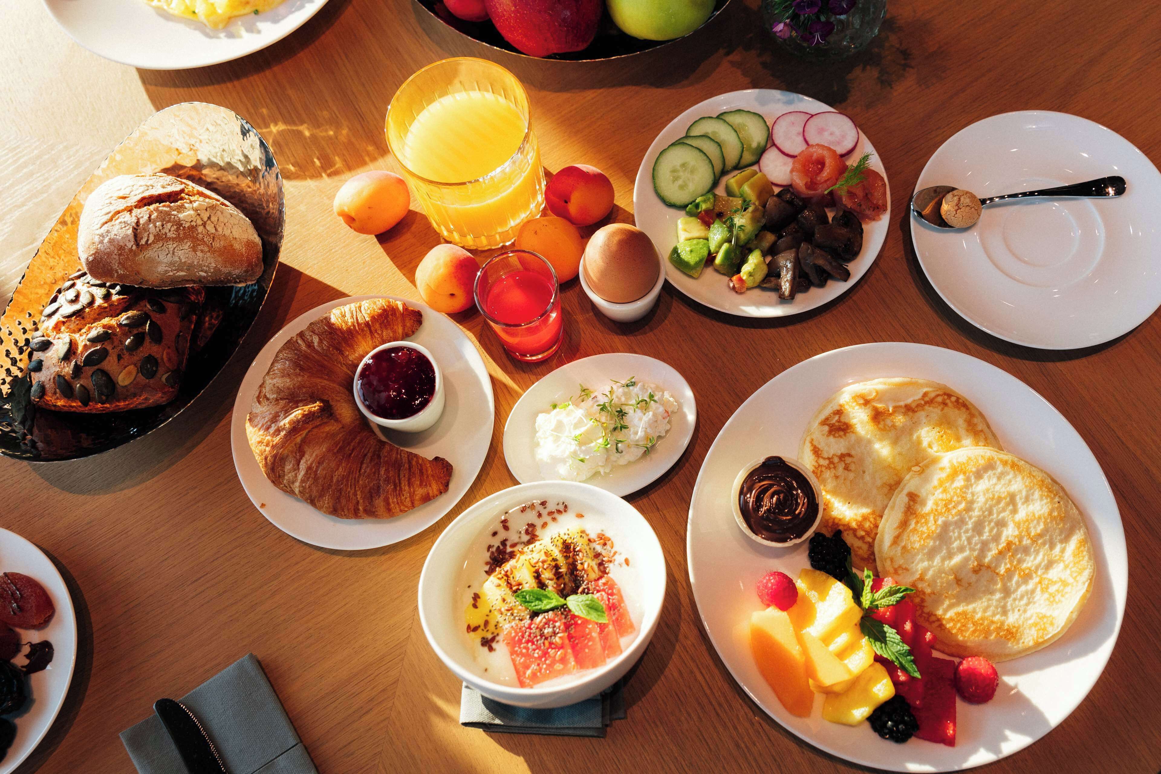 A breakfast spread with various foods and drinks on a wooden table.