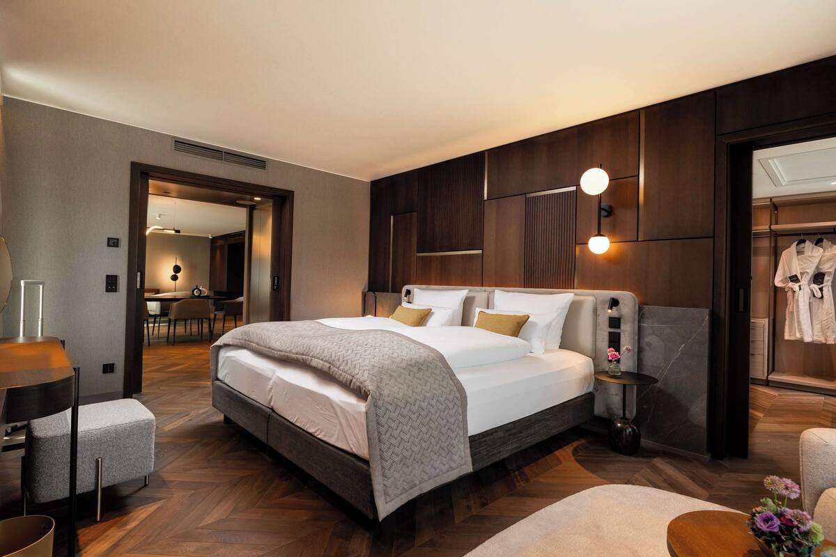 A modern hotel room with a large bed, a desk, and a bathroom visible through an open door.