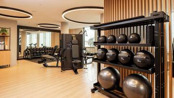 Ein Fitnessraum mit Trainingsgeräten, Gewichten und einem Spiegel.