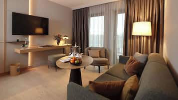 A modern living room with a flat-screen TV, a round coffee table with fruits, a sofa, and a chair.