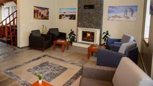 A living room with a fireplace, sofas, a coffee table, and a staircase. - Ahıska Palas (Kars)