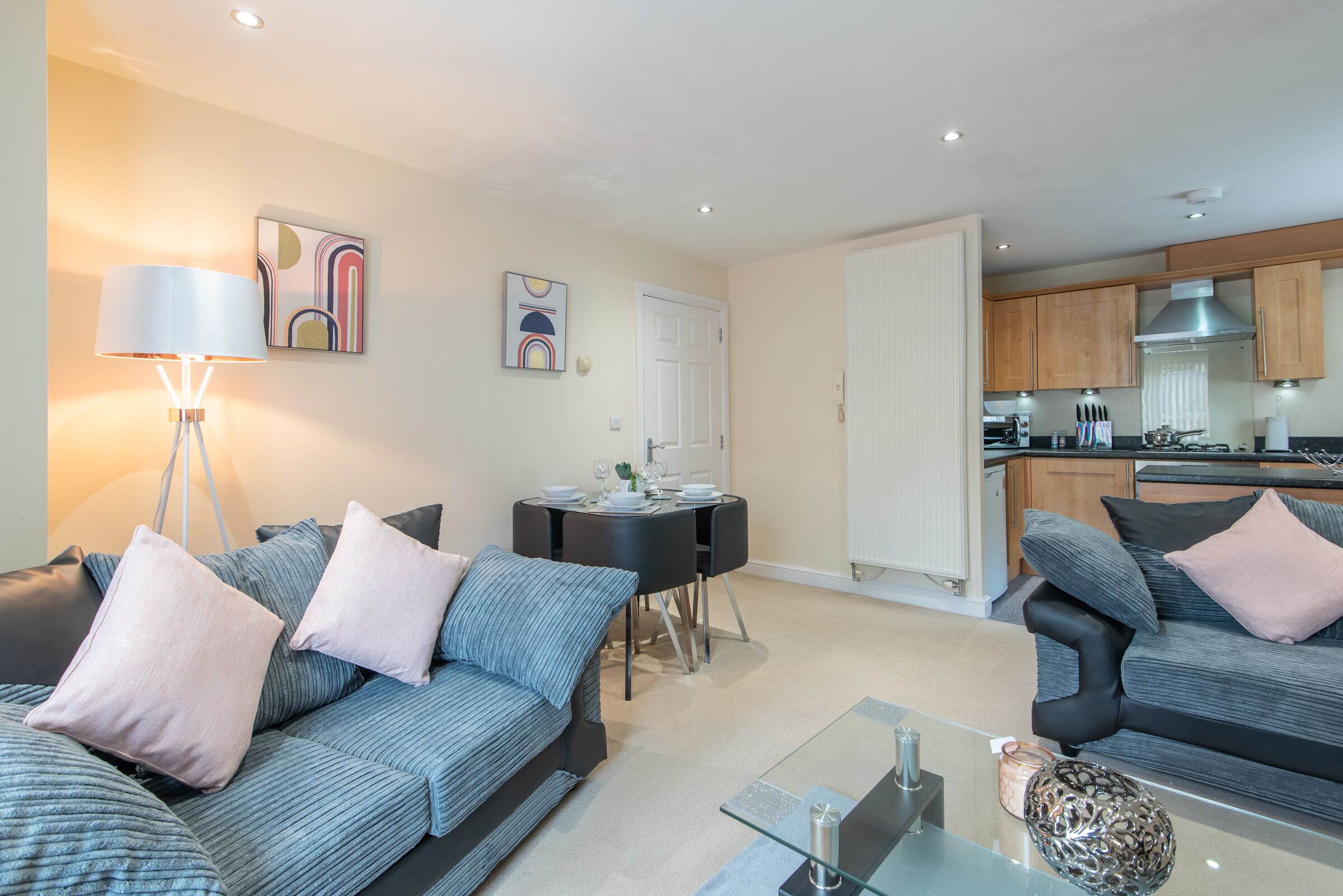 A modern living room with a sofa set, a glass coffee table, and a dining area with a table and chairs.