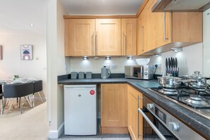 Una cocina compacta con armarios de madera, un refrigerador blanco, una estufa y un microondas.