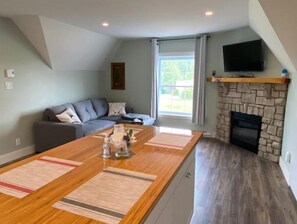 A modern living room with a sofa, a fireplace, and a television mounted on the wall. - Relax, Zen condo, with AC, country side & lakes (Stanstead)