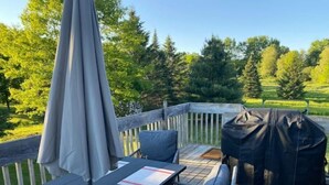 Une terrasse avec une table et des chaises, un barbecue et un parasol.