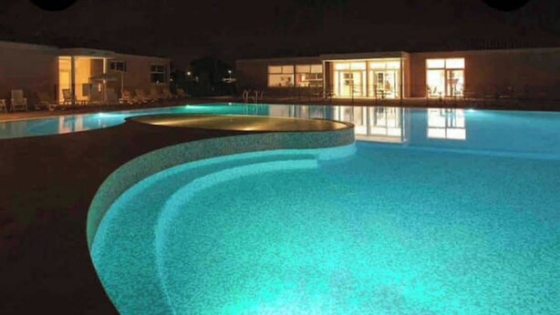 A nighttime swimming pool with illuminated edges, surrounded by lounge chairs and a building with large windows. - Fully-equipped bastidon in the heart of the Ventoux (Aubignan)