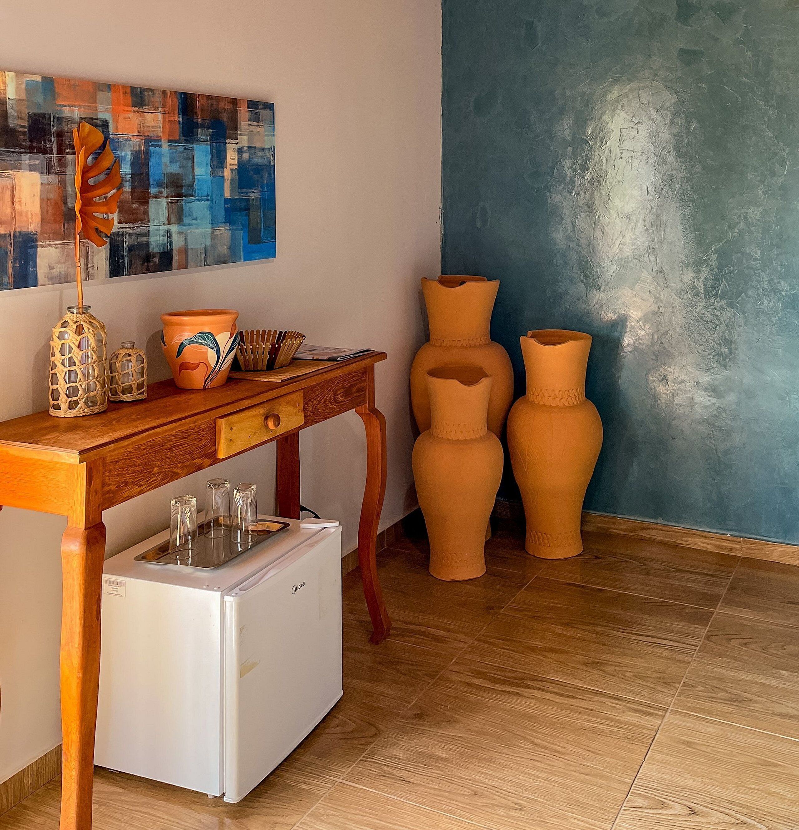 A kitchen with a wooden table, a white refrigerator, and three terracotta pots.