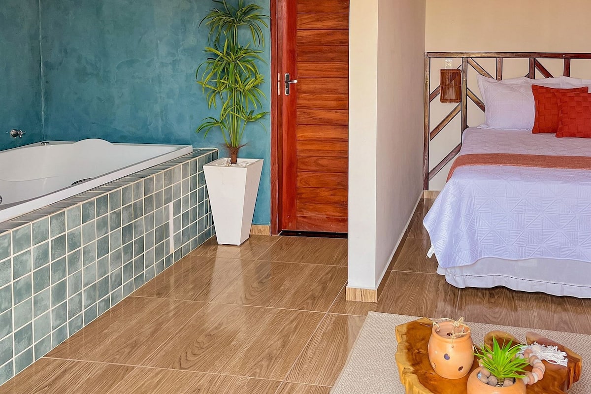 A modern bathroom with a bathtub, a wooden door, and a potted plant.