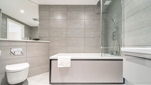 A modern bathroom with a bathtub, toilet, and shower. - Seven Living Solihull - Broadoaks Studio (Solihull)