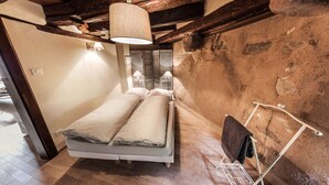 A small, rustic bedroom with a wooden bed, a hanging light fixture, and a towel rack. - Cottage 'BRAND (Turckheim)