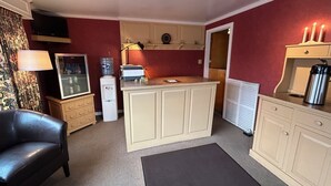 Eine kleine Küche mit Kühlschrank, Wasserspender, Kaffeemaschine und Mikrowelle.