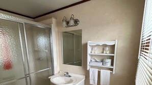 Ein Badezimmer mit Duschkabine aus Glas, Waschbecken, Toilette und Schminktisch.