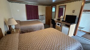 Ein Hotelzimmer mit zwei Betten, einem Schreibtisch, einem Fernseher und einer Mikrowelle.