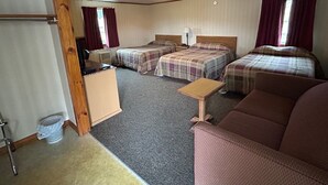 Ein kleines Hotelzimmer mit zwei Betten, einem Schlafsofa, einem kleinen Tisch und einem Schreibtisch.