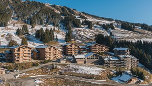 Une station de ski avec des bâtiments à plusieurs étages, un ciel dégagé et un paysage enneigé.