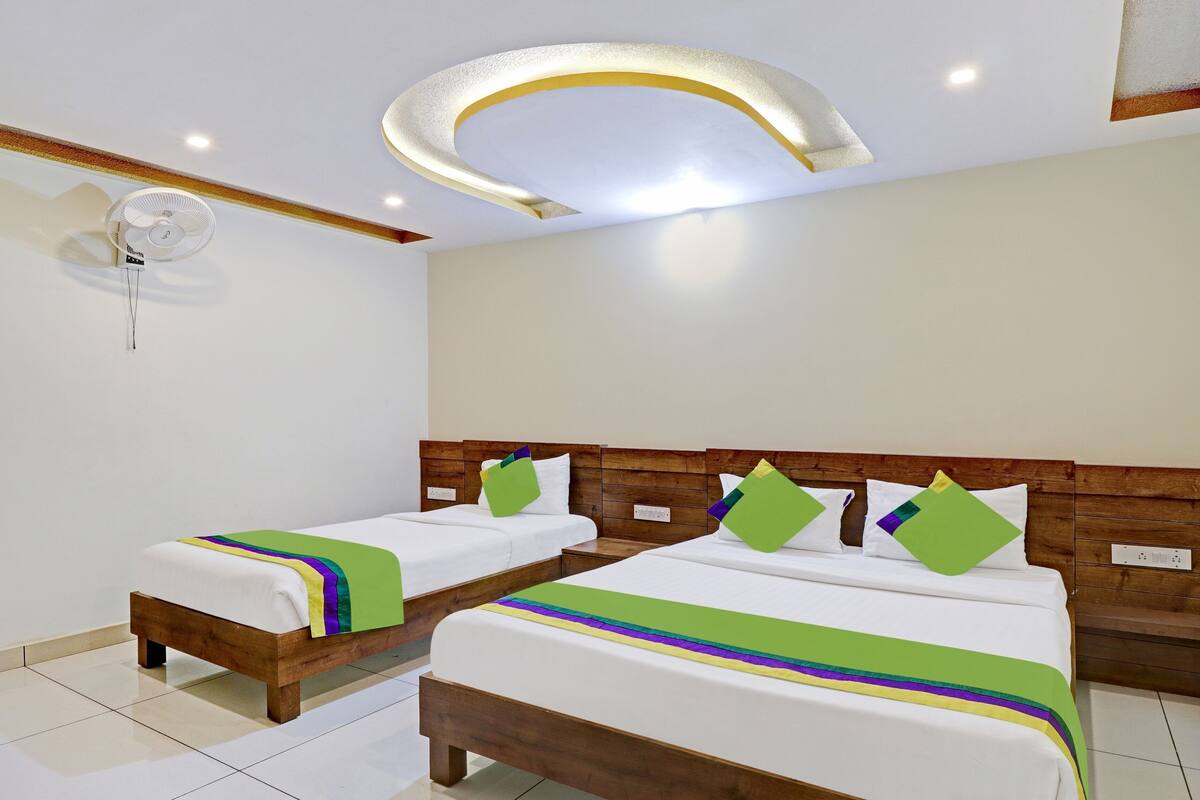 Quarto de hotel com duas camas, um ventilador de teto e uma luminária moderna.