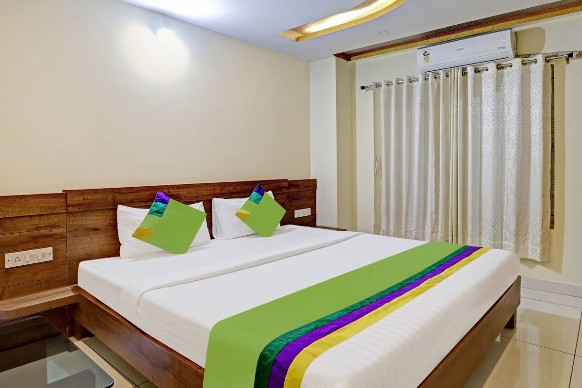 Cama bem arrumada com edredom branco e manta listrada colorida.