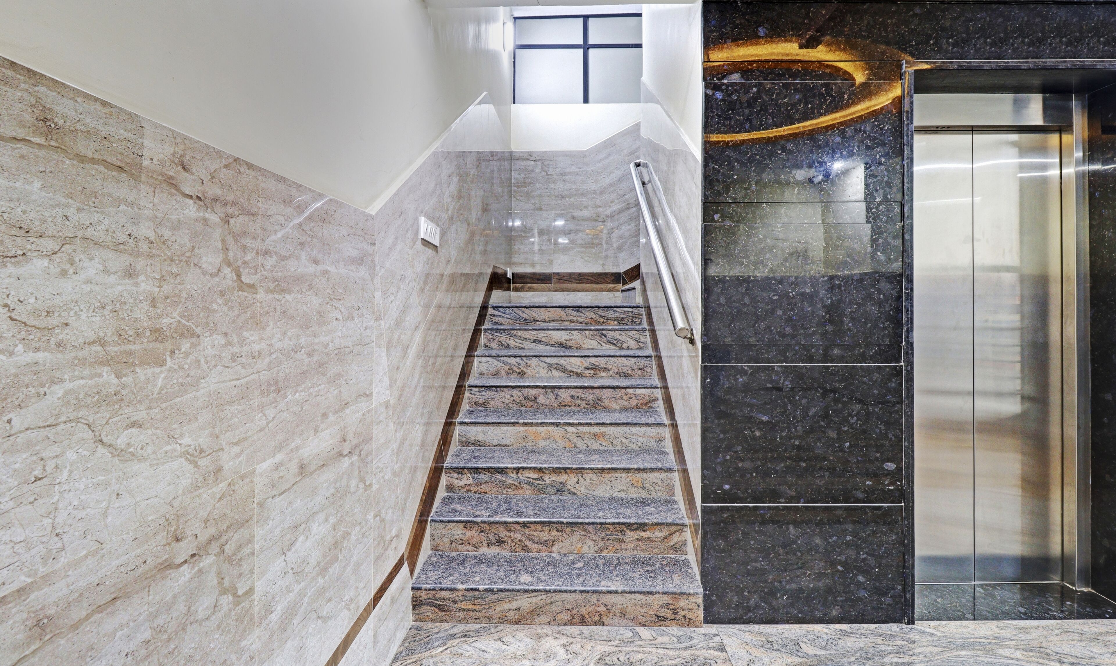 A marble staircase leading to an elevator in a modern building.