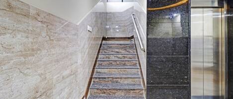 A marble staircase leading to an elevator in a modern building.