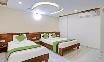 Habitación de hotel con dos camas de madera, ropa de cama blanca y una lámpara de techo moderna.