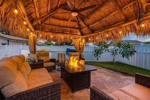 Sit under the romantically lit tiki hut with a gas-powered firepit, outdoor lounging with a smart ROKU TV and sound bar.