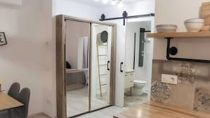 Una cocina moderna con encimera de madera, una mesa de comedor con sillas y una puerta corredera que da a un dormitorio.