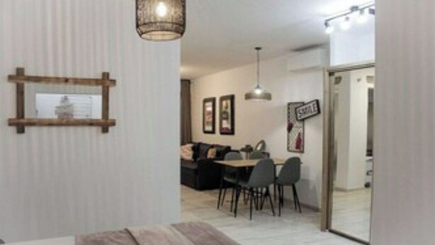 Una sala de estar moderna con un sofá, una mesa de comedor y sillas. Hay un banco de madera y una lámpara colgante.