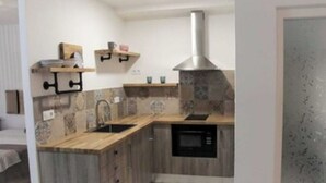 Una cocina compacta con armarios de madera, un microondas integrado y una campana extractora de acero inoxidable.