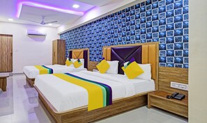 A hotel room with two beds, a wooden headboard, a wall with blue patterned tiles, a ceiling fan, and a bedside phone.