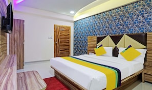 A hotel room with a bed, wooden headboard, a red carpet, and a wall with a geometric pattern. - Itsy Hotels Rk Palace (Vadodara)