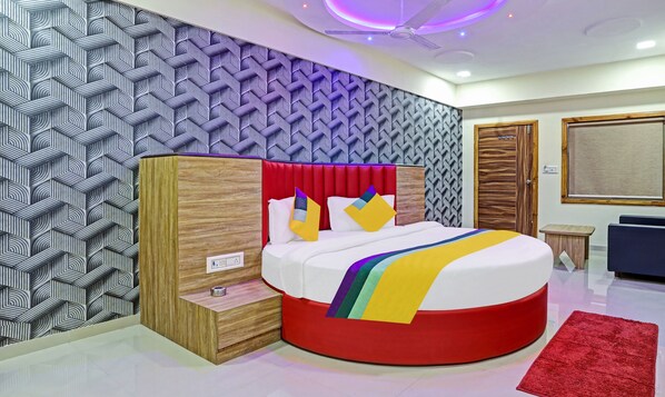 A modern bedroom with a circular bed, a wooden wardrobe, and a red accent wall.