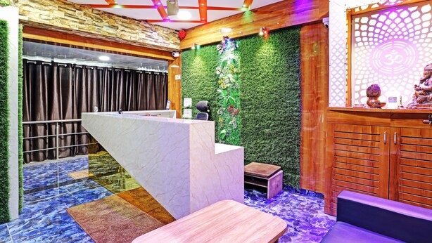 A reception area with a marble counter, a green wall with decorative elements, and a wooden cabinet with drawers. - Itsy Hotels Rk Palace (Vadodara)