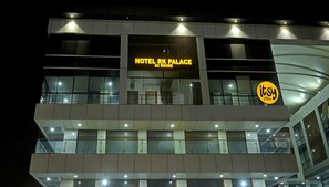 A hotel building with a sign reading "HOTEL RK PALACE AC ROOMS".