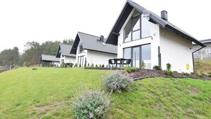 A modern two-story house with a sloped roof, large windows, and a well-maintained lawn.
