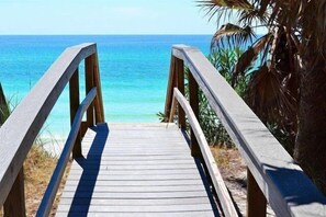 A wooden boardwalk leading to a beach with clear blue water and palm trees. - Walkabout 30A - Pickleball / Deeded Beach Access / 3 Pools (Santa Rosa Beach)