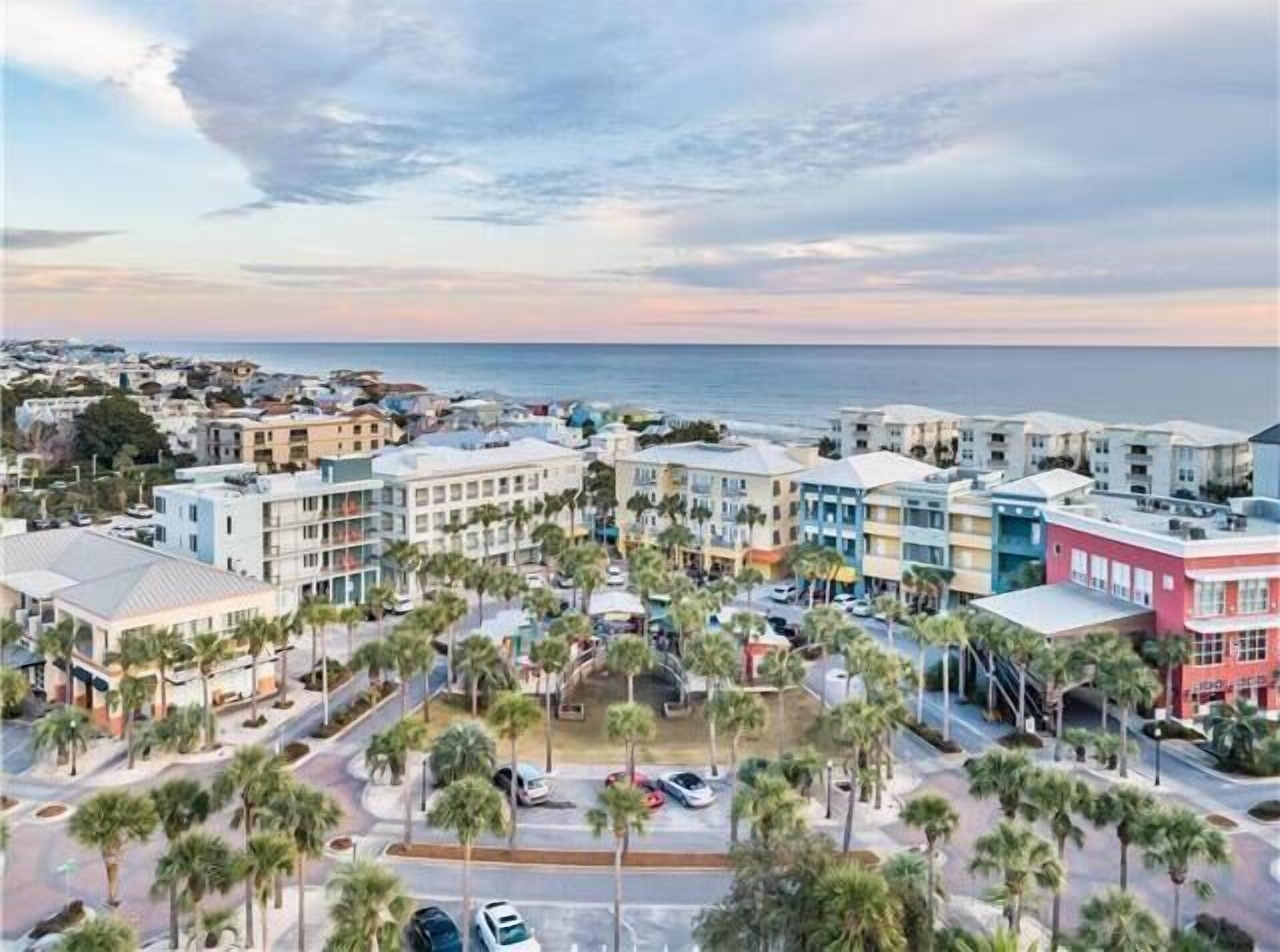 A coastal residential area with multi-story buildings, palm trees, and a view of the ocean.
