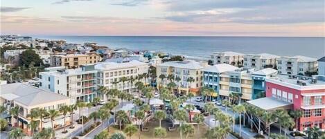 A coastal residential area with multi-story buildings, palm trees, and a view of the ocean.