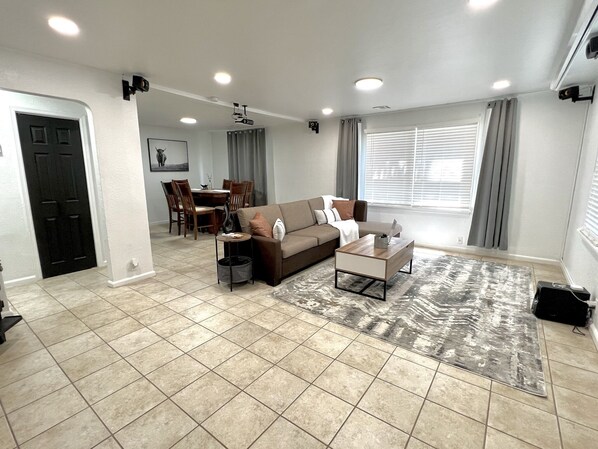 A spacious living area with a sofa, coffee table, and dining table.