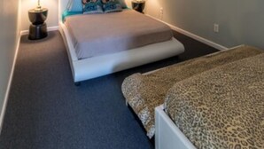 Ein Schlafzimmer mit schräg laufender Decke, einem Bett mit Leopardenmuster und zwei Nachttischlampen.