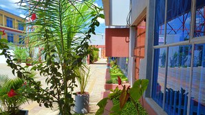 A pathway lined with potted plants and a building with large windows. - Montana Guest Resort Naivasha  (Naivasha)