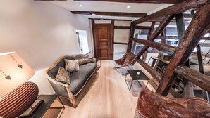 A cozy living room with a sofa, a chair, a wooden coffee table, and a lamp. - Gite 'WATCHER (Turckheim)