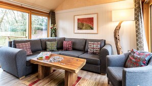 A cozy living room with a sectional sofa, a wooden coffee table, and a large window. - Lodge 7 (Wareham)