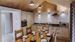 A modern kitchen with wooden cabinets, a granite countertop, and pendant lighting. - Lodge 7 (Wareham)