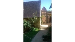 Un sendero de grava que conduce a un edificio con techo de tejas y un arco de piedra.